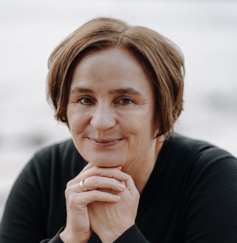 Nicole Breuer Köln Supervisorin und Beraterin - NEUE BLICKWINKEL Nicole Breuer, systematische Beraterin und Supervisorin aus Köln, am Rhein hockend